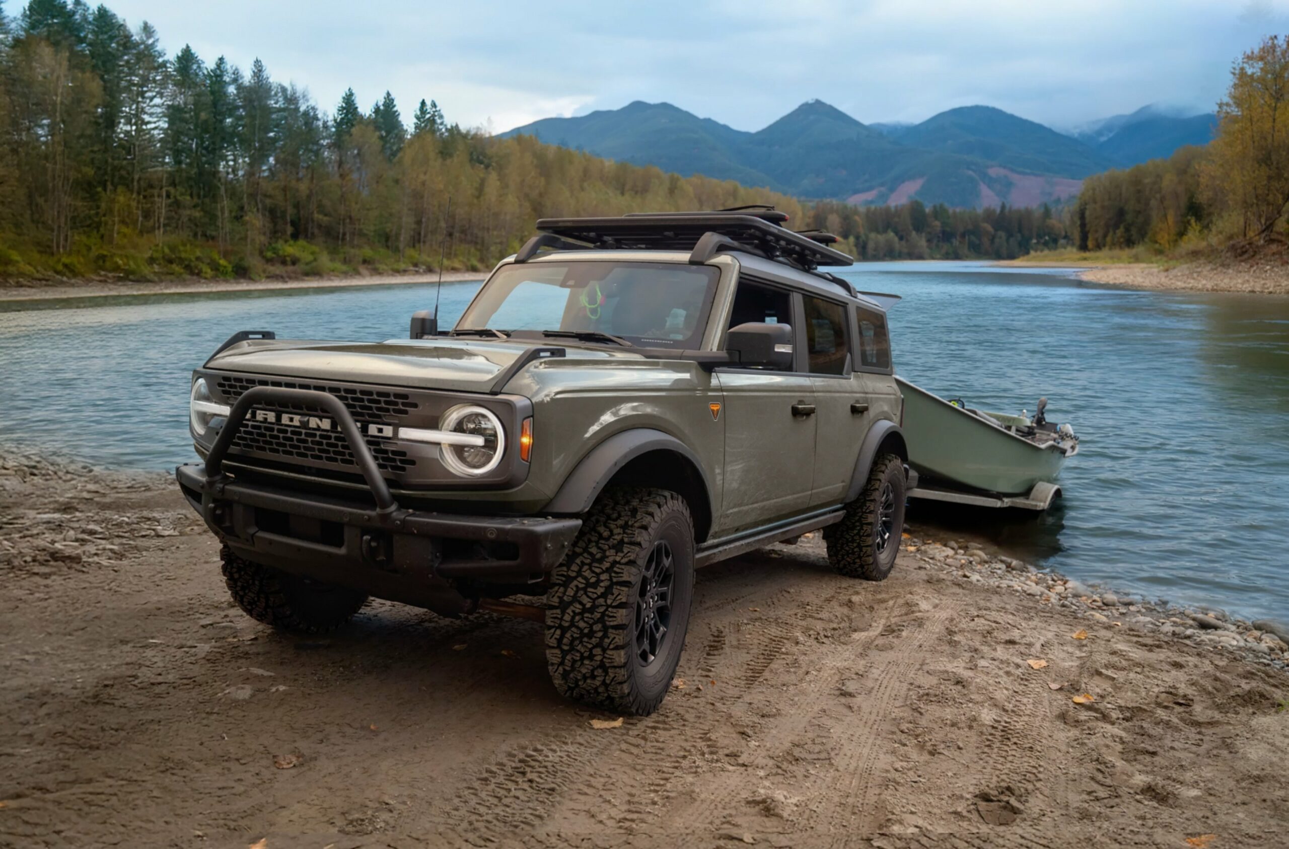 A 2026 Ford Bronco towing a boat trailer beside a river