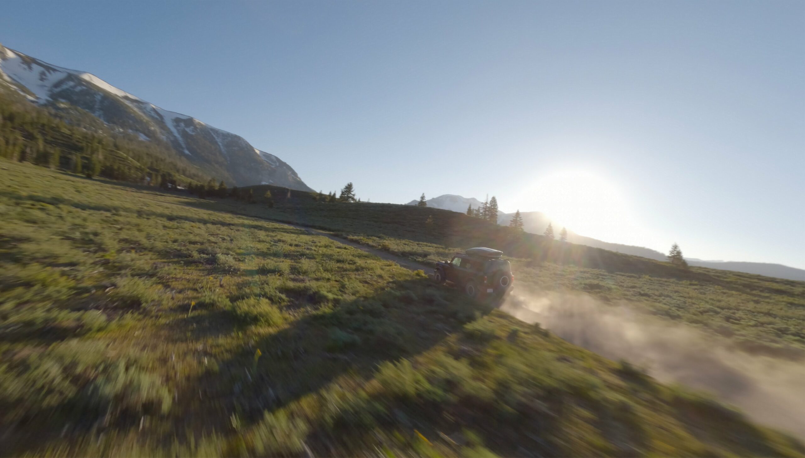 A 2026 Ford Bronco driving through dust at sunset