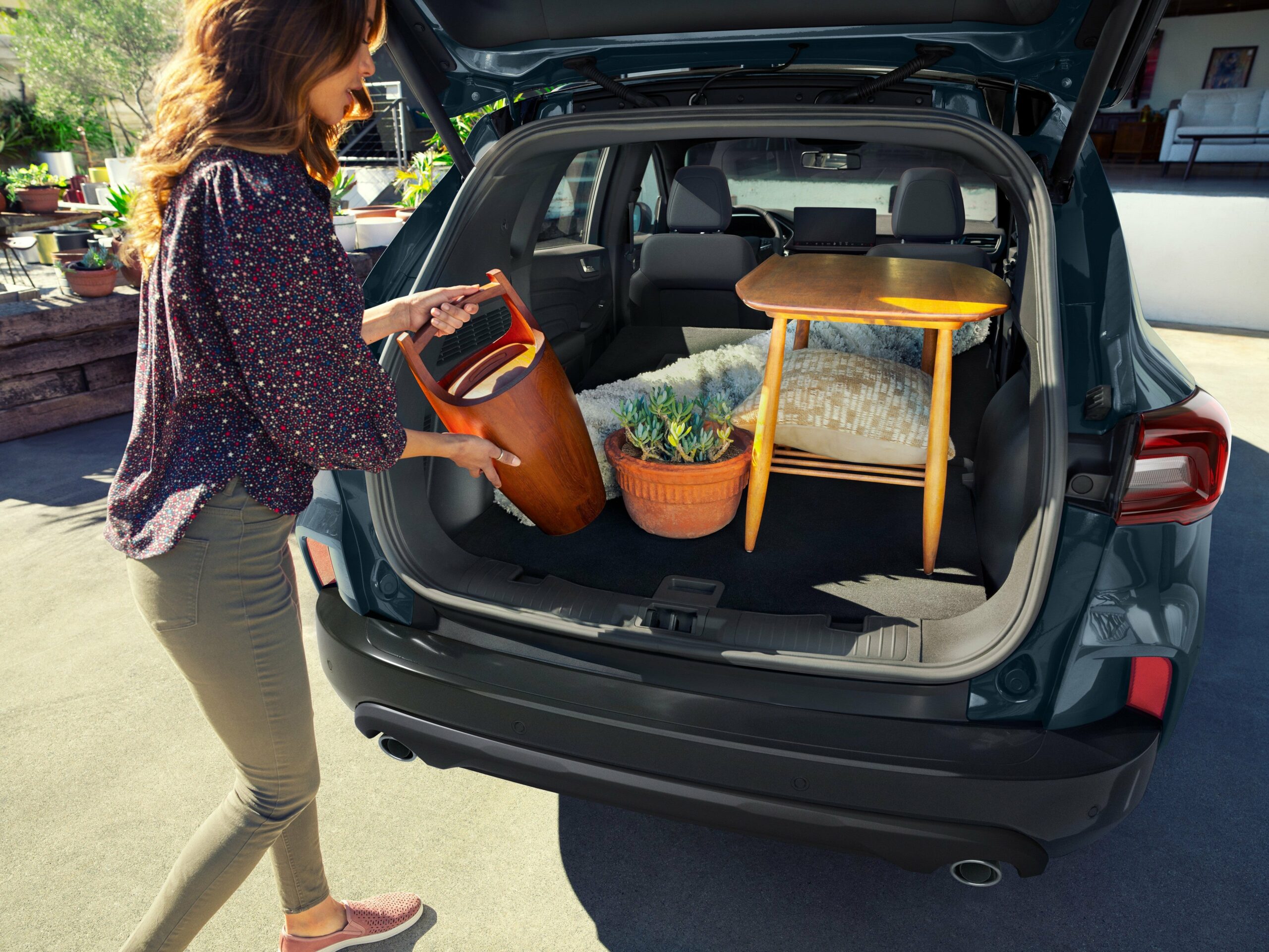 A person loading bags through the open tailgate of a 2026 Ford Escape