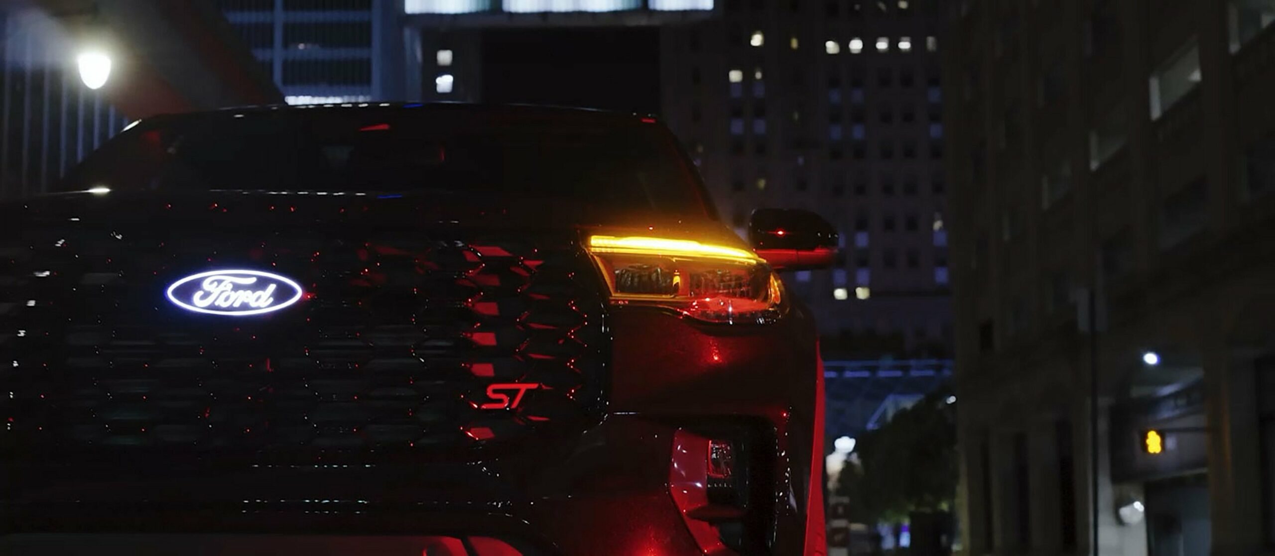 The lit tail lamps of a 2027 Ford Explorer ST with the Sinister Package at night