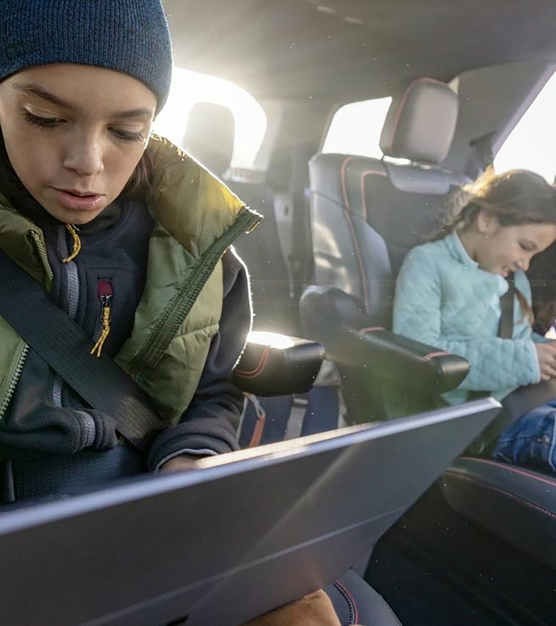 Two children sitting in the third row of a 2027 Ford Explorer using tablets
