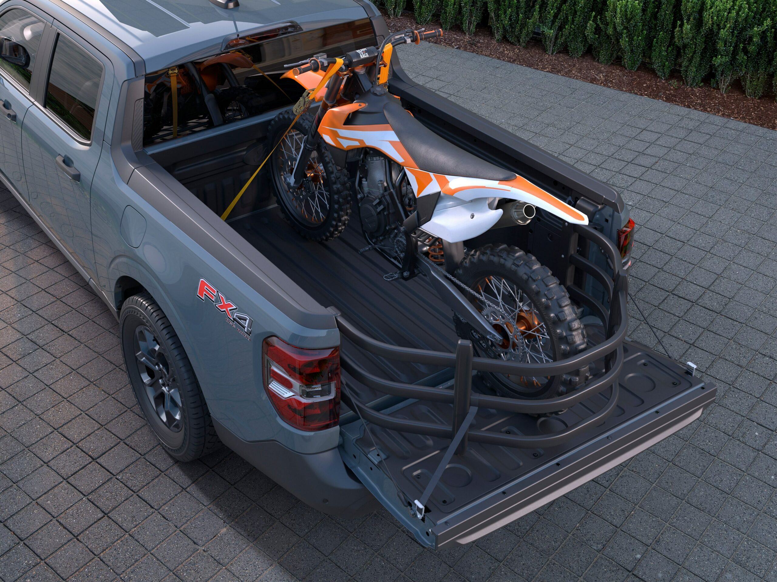 A gray 2026 Ford Maverick with the FX4 badge, tailgate down and a dirt bike strapped into the bed