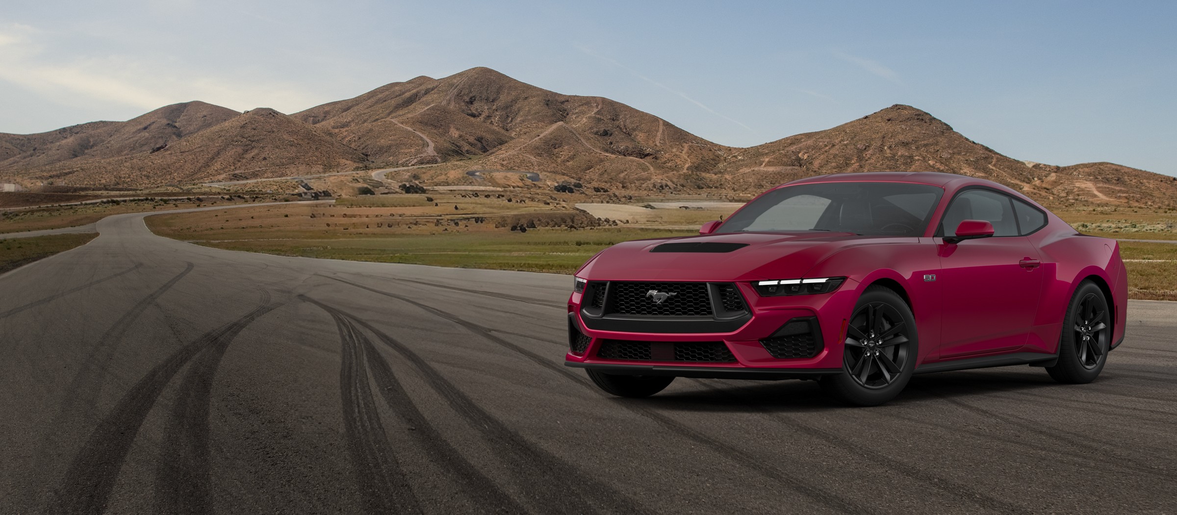A dark red 2026 Ford Mustang GT Fastback with hood vents on a desert road