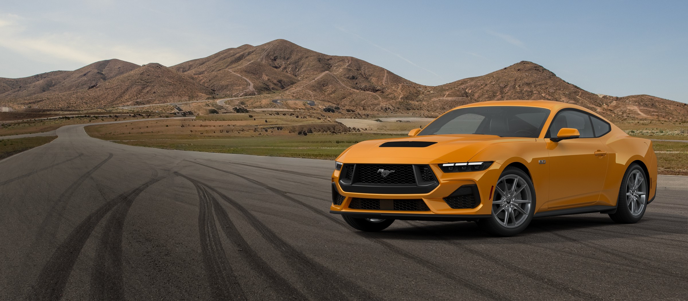 An orange 2026 Ford Mustang GT Premium Fastback on a desert road