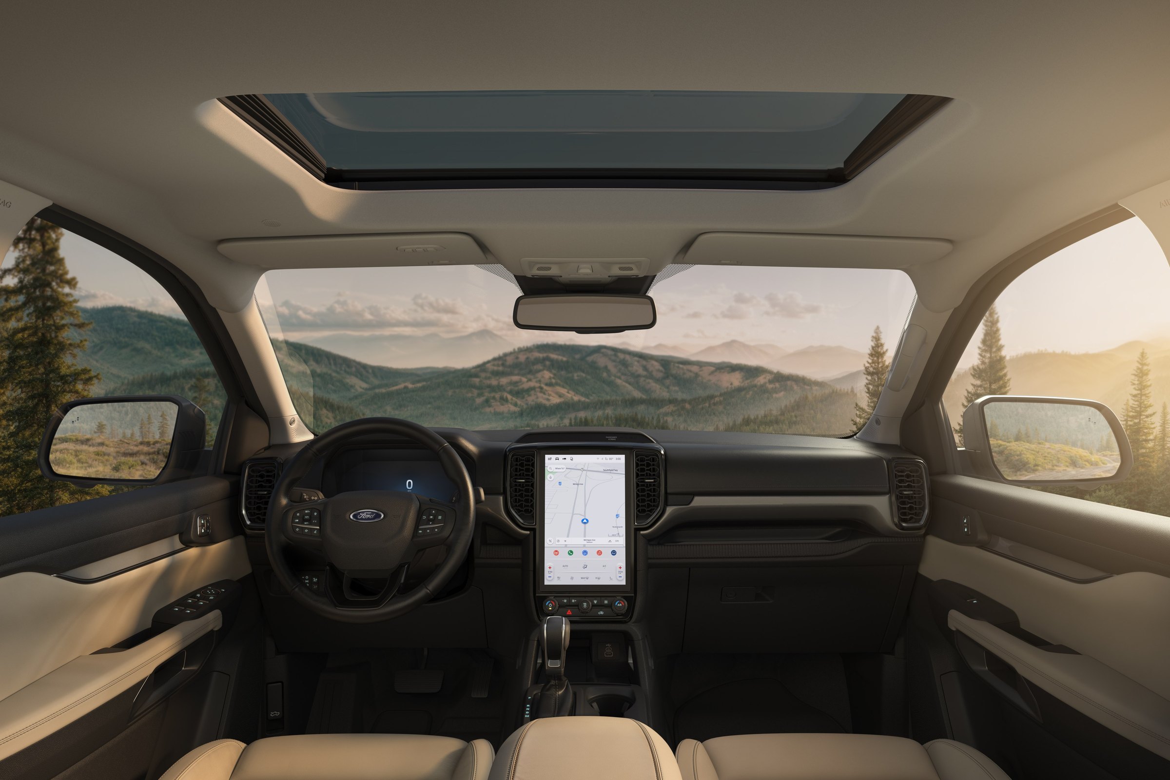The cabin of a 2026 Ford Ranger Lariat in sandstone, seen from the back seat with the panoramic moonroof open and a portrait touchscreen showing a map, mountains through the windows