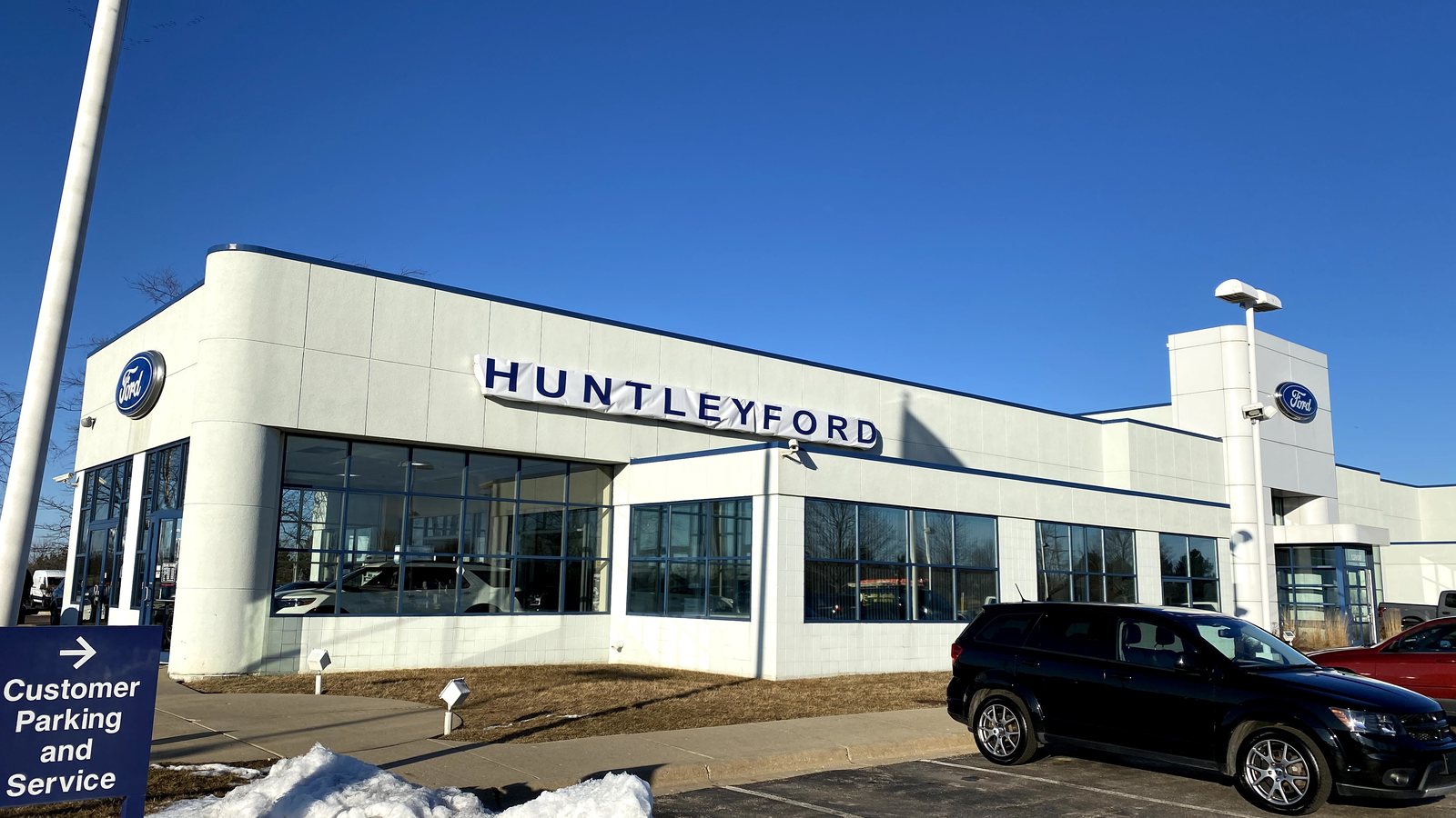 The Huntley Ford showroom on a winter day, with a sign pointing to customer parking and service