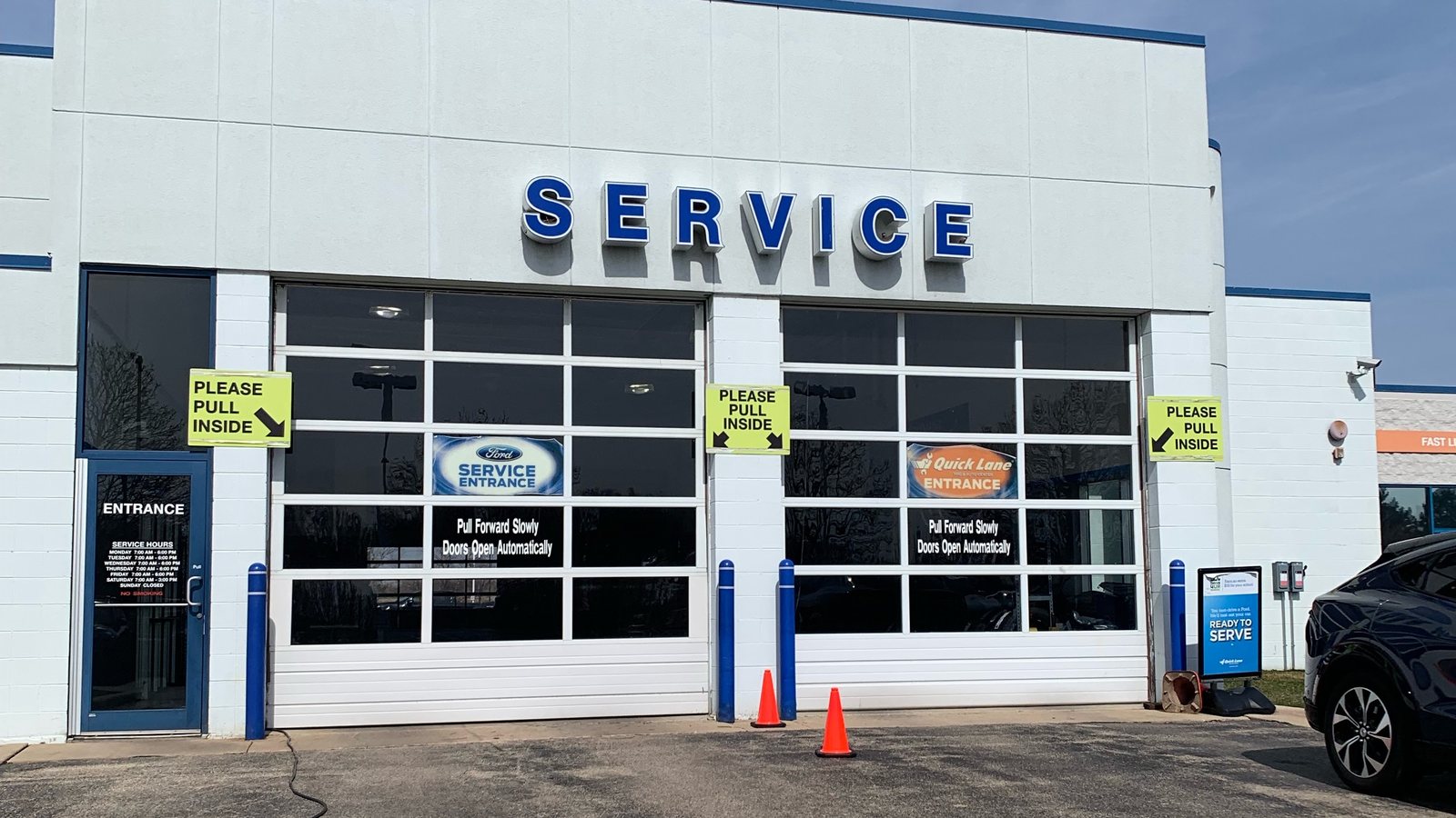 The Huntley Ford service drive entrance: two glass bay doors under a SERVICE sign, with signs asking drivers to pull inside
