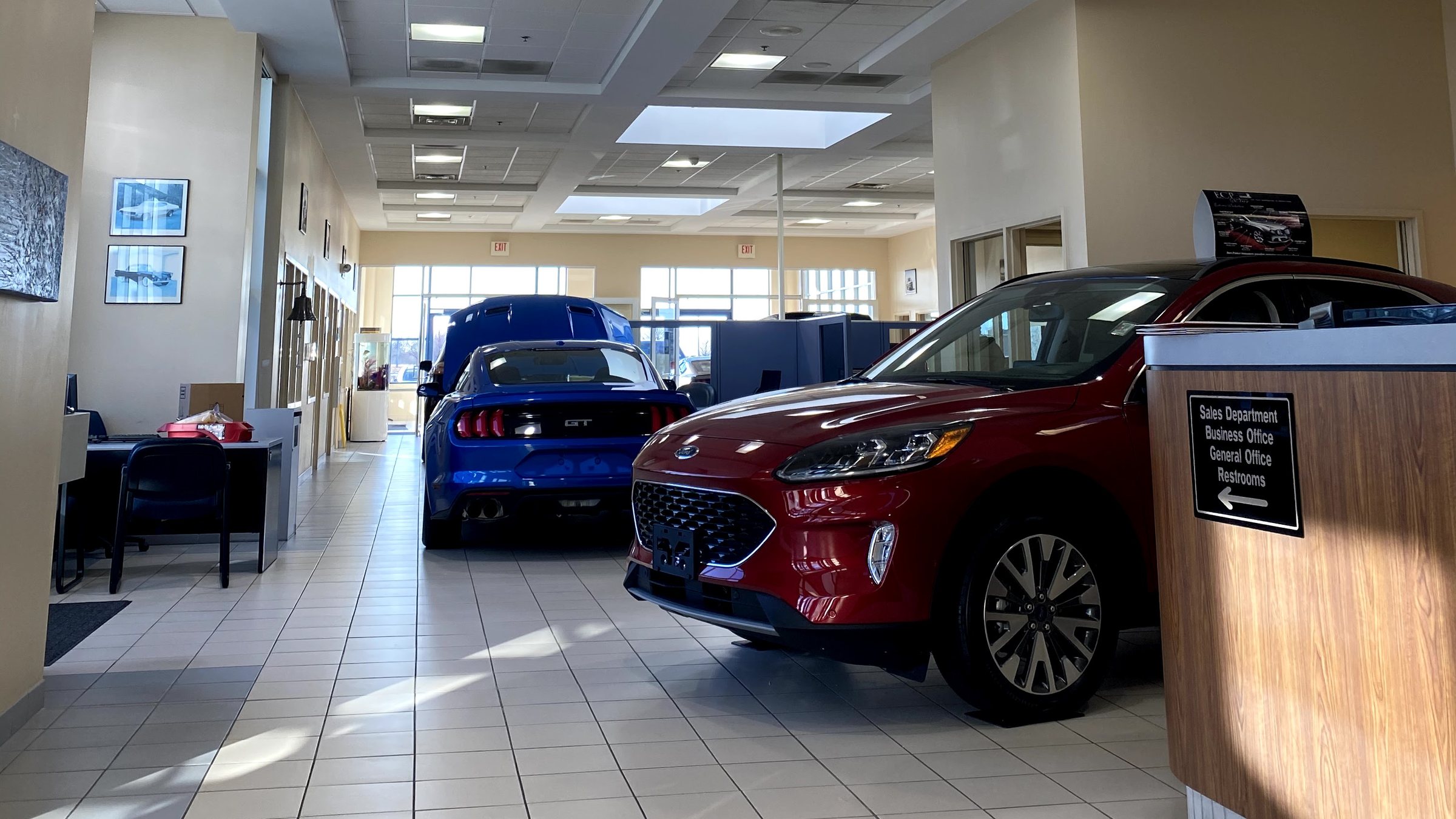 The Huntley Ford showroom floor beside the front desk, where a sign points to the sales department, business office, and restrooms